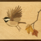 Photo of wood art depicting chichadee and maple twig with leaves